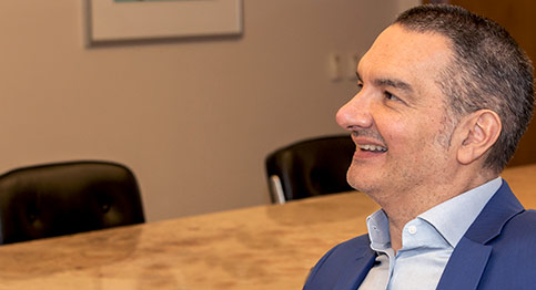 A in-profile picture of Roberto Quiroga, smiling. He is wearing a dark blue jacket and a light blue shirt.